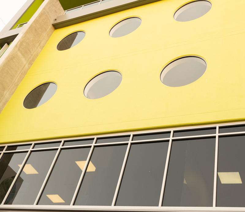 Modern yellow building facade with circular windows.